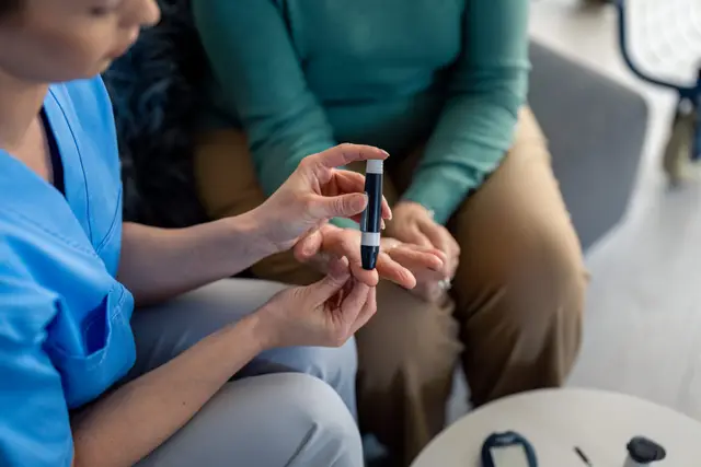 A healthcare professional demonstrates the use of a medical device to a patient in a casual setting.