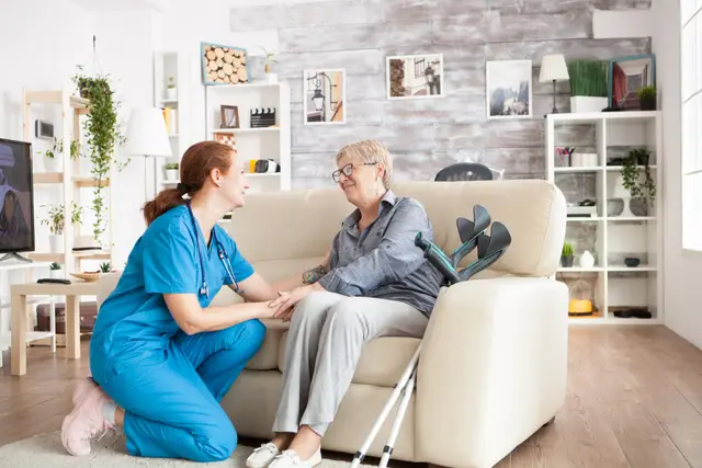 A caregiver talks warmly with an elderly woman in a cozy living room, promoting a sense of comfort and companionship.